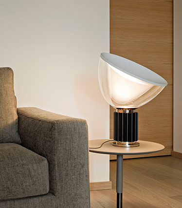Nowoczesna designerska lampa, która zapewnia miękkie, nastrojowe oświetlenie obok współczesnej sofy.