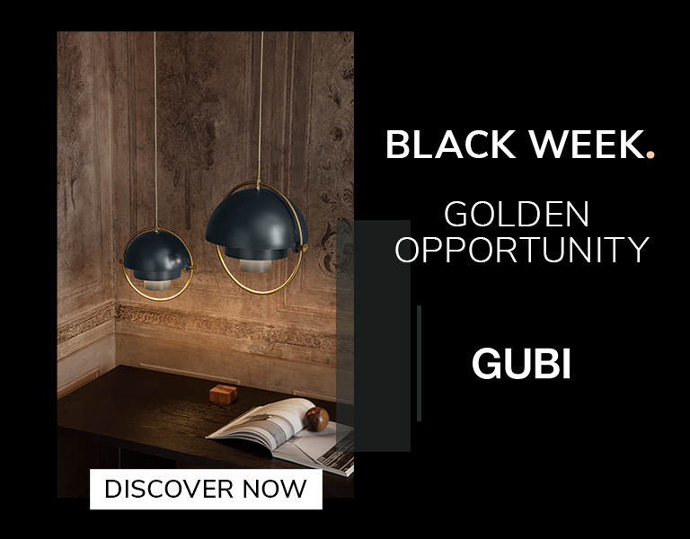 Discover more Two modern pendant lamps with dark blue domes and gold accents hanging above a wooden desk in a warmly lit, ornate room. Text reads: ‘Black Week. Golden Opportunity. GUBI.’ A button says ‘Discover Now.’