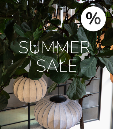 Materiałowe lampy wiszące na tle bujnej zieleni z informacją o Summer Sale.