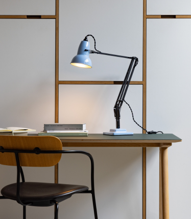 Jasnoniebieska lampka biurkowa Anglepoise na drewnianym stole z krzesłem